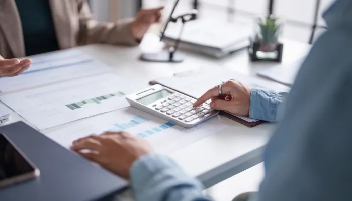 Person calculating finances with reports and charts